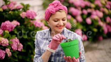 快乐的女人花匠。 护花和浇水.. 土壤和肥料。 女人在花园里照料鲜花